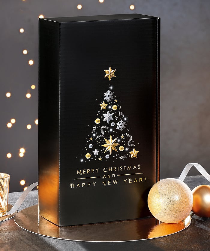 A black corrugated gift box decorated with Christmas ornaments in a festive setting.