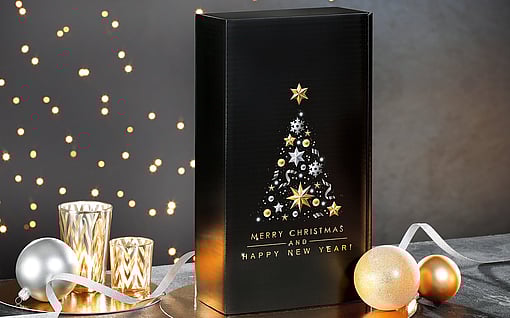 A black corrugated gift box decorated with Christmas ornaments in a festive setting.