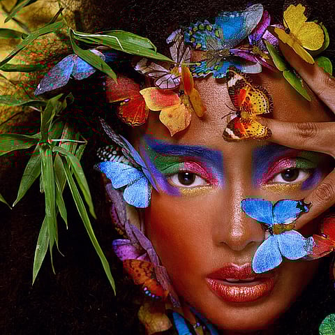 A woman surrounded by vibrant leaves and butterflies.