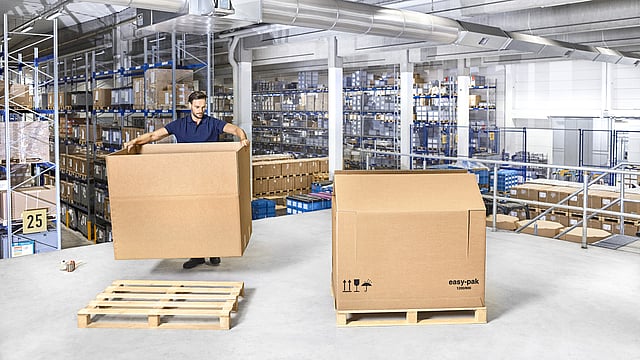 A person assembling a corrugated box for heavy goods.