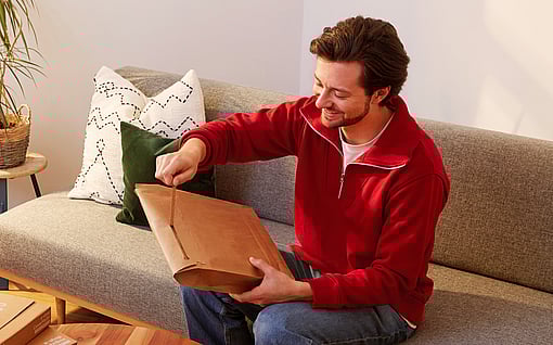 A man using a tear-off strip to open a package.