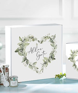A white corrugated gift box featuring a floral heart-shaped design and the inscription in German, "Alles Gute."