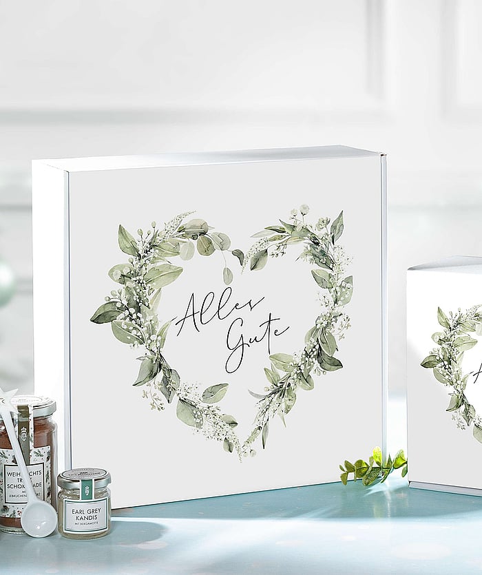 A white corrugated gift box featuring a floral heart-shaped design and the inscription in German, "Alles Gute."