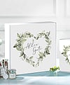 A white corrugated gift box featuring a floral heart-shaped design and the inscription in German, "Alles Gute."