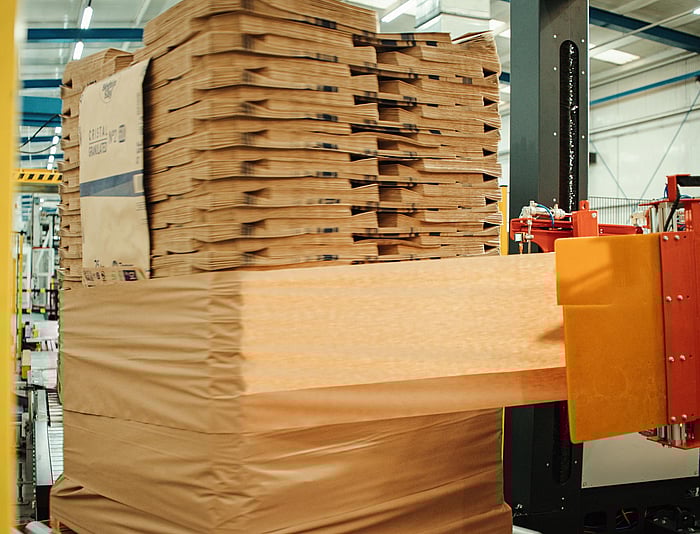 Gestapelte Paletten, in Schutzmaterial verpackt, werden in einem Lager mit industrieller Ausrüstung bewegt.