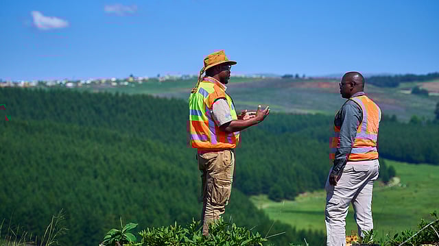 Two engineers to Mondi uniforms walking against a backdrop of a pulp mill.