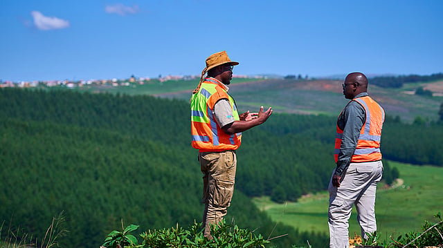 Two engineers to Mondi uniforms walking against a backdrop of a pulp mill.