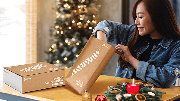 A woman in a room decorated for Christmas is unpacking items from a Mondi MailerBag und Mondi SupremeBox