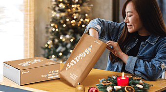 A woman in a room decorated for Christmas is unpacking items from a Mondi MailerBag und Mondi SupremeBox