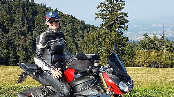 Photograph of Kerstin Zucker from Mondi Ansbach sitting on top of her motorcycle in front of a natural landscape.