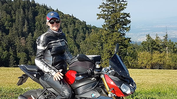 Photograph of Kerstin Zucker from Mondi Ansbach sitting on top of her motorcycle in front of a natural landscape.