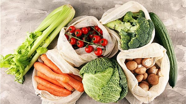 there are different types of vegetables on a grey background. There are tomatoes, cucumber, carrots, cabbage and broccoli.