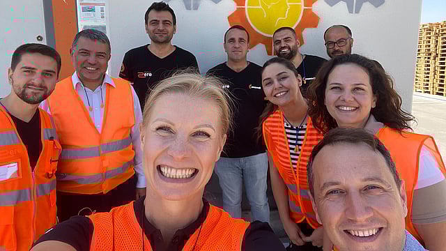 Group of workers in orange vests talking a selfie in front of Mondi branded signs
