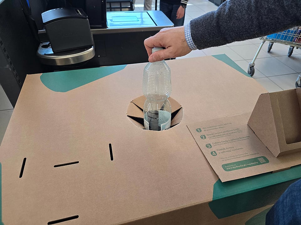 hand placing a plastic bottle into a recycling box